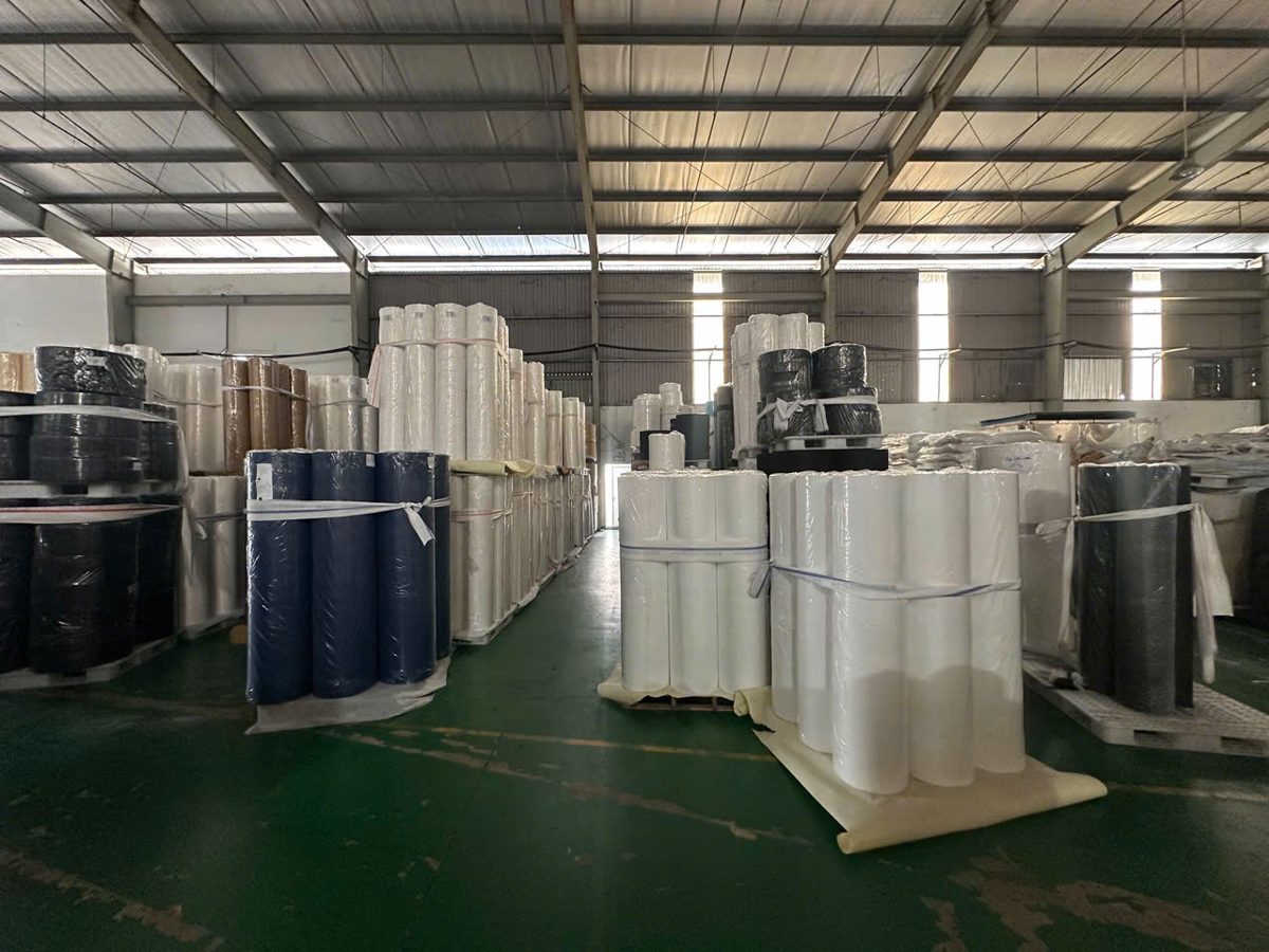 Kho vải không dệt An Phong với các cuộn trắng, đen, xanh chờ giao